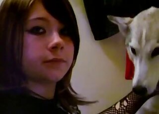 Dark-haired emo girl is having lots of fun with a cute white dog
